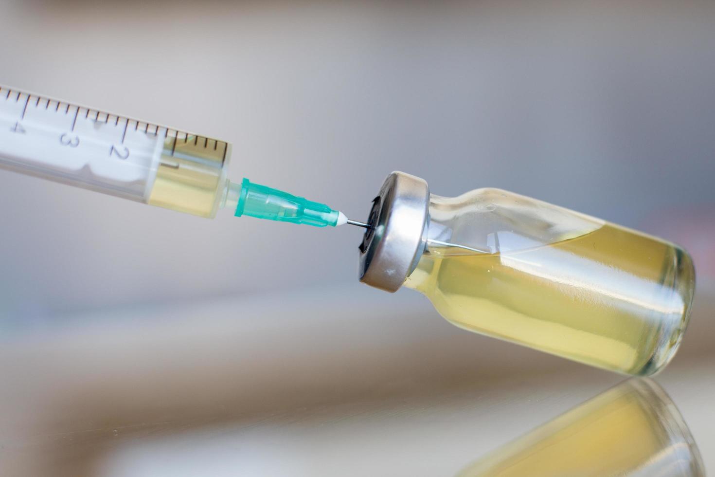 Fläschchen gefüllt mit flüssigem Impfstoff im medizinischen Labor mit Spritze. medizinische ampulle und spritze auf der glasoberfläche foto