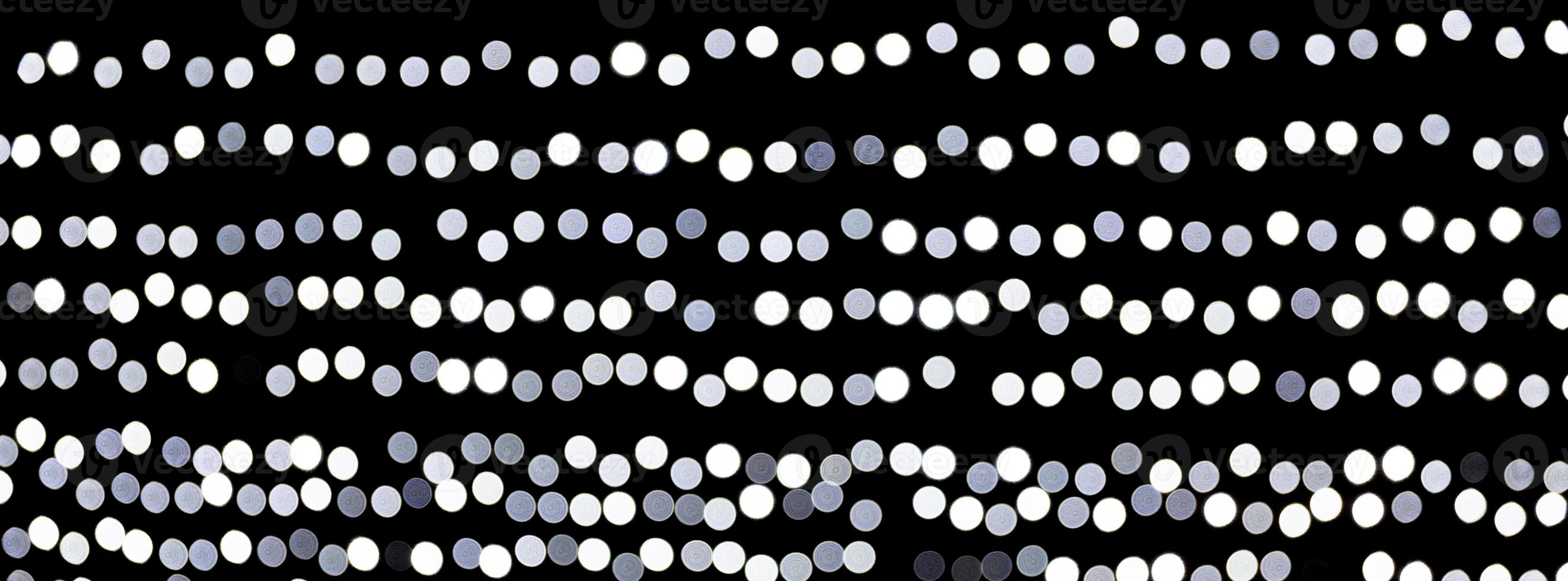 abstraktes bokeh der weißen stadtlichter auf schwarzem hintergrund. defokussiert und verschwommen viele runde licht foto