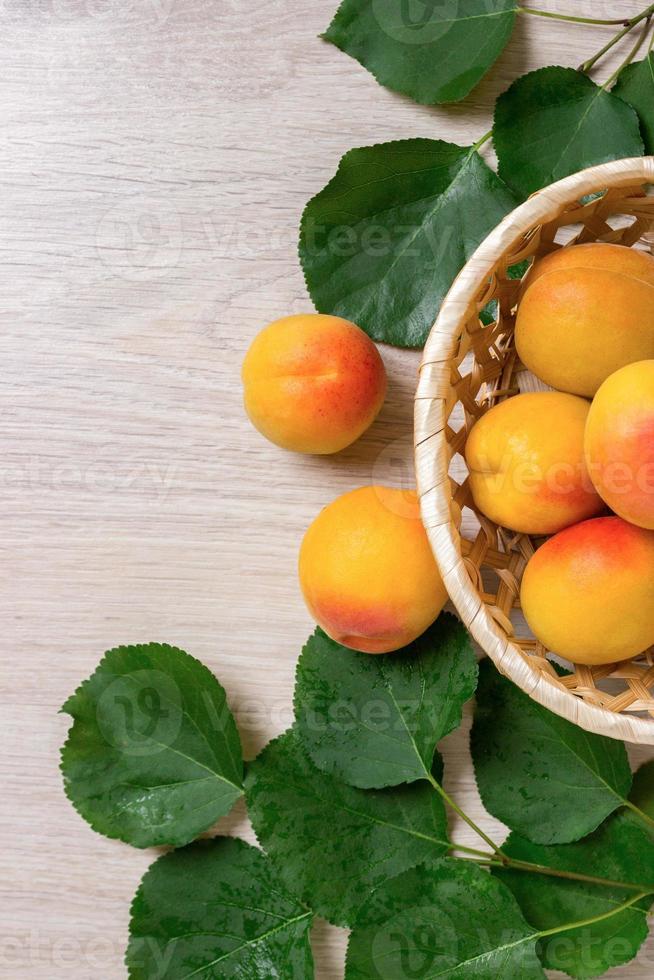 frische Aprikosen im Korb auf einem Holztisch foto