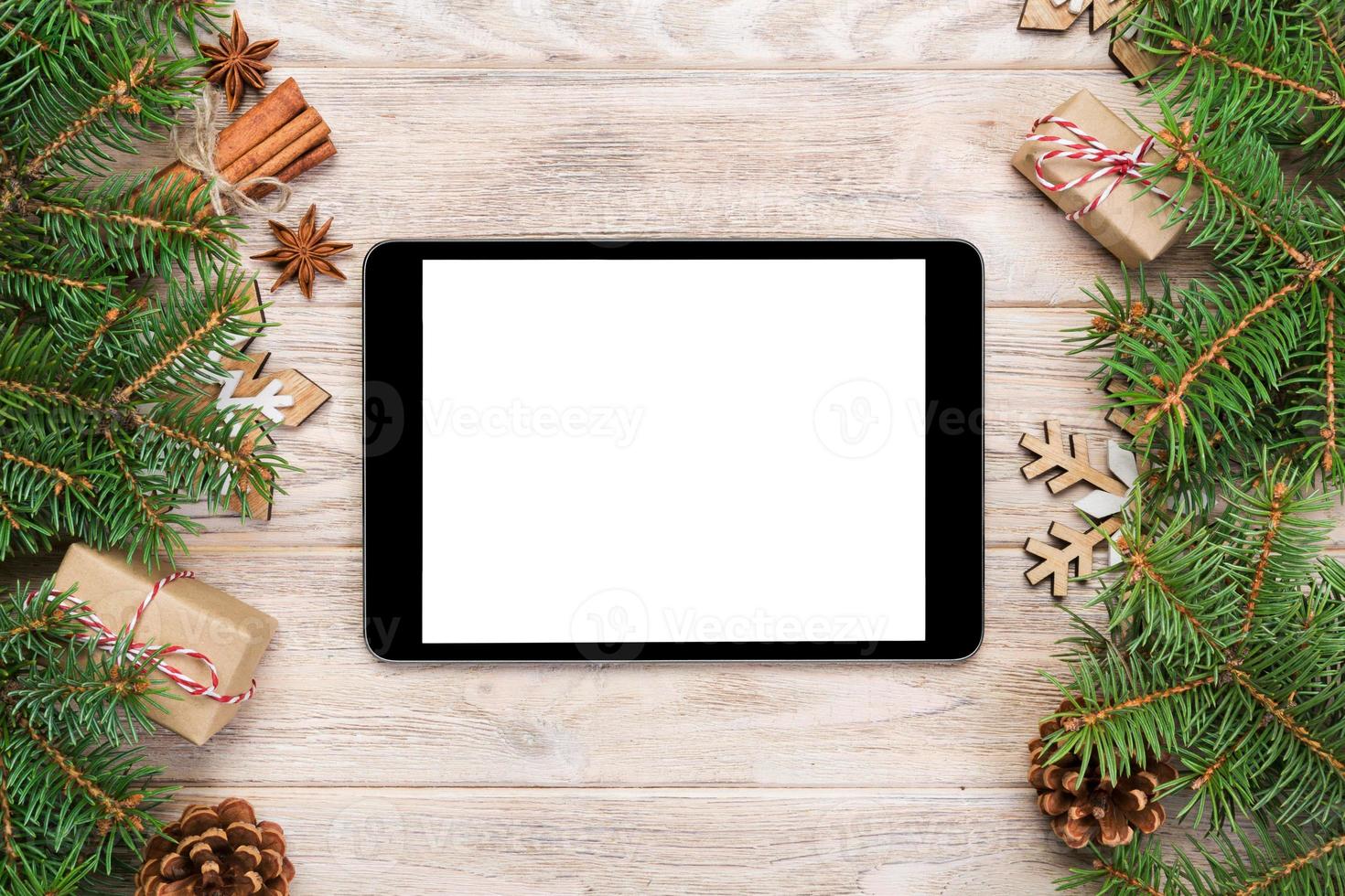 digitales tablet-modell mit rustikalen weihnachtsholzhintergrunddekorationen für app-präsentation. draufsicht mit kopierraum foto