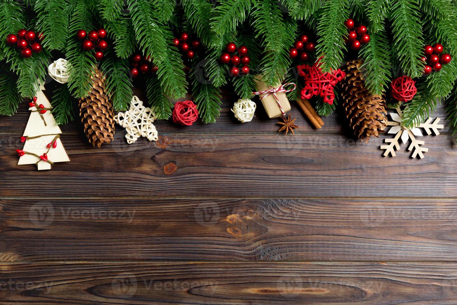 Draufsicht des Rahmens aus Tannenzweigen und Feiertagsdekorationen auf Holzhintergrund. weihnachtskonzept mit leerem raum für ihr design foto