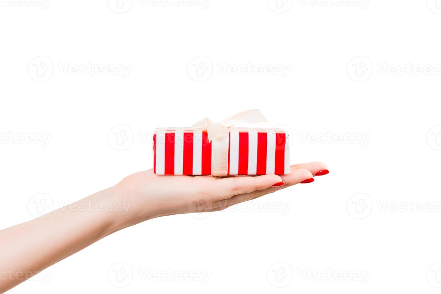 frauenhände geben eingewickeltes weihnachts- oder anderes handgemachtes geschenk in rotem papier mit goldband. isoliert auf weißem Hintergrund, Ansicht von oben. Thanksgiving-Geschenkbox-Konzept foto