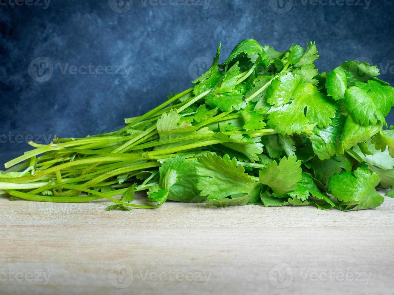 ein Bund Koriander auf einem Schneidebrett. nützliches Produkt. Gemüse auf dem Küchentisch. vegetarische zutat für das mittagessen. viele Korianderstiele foto