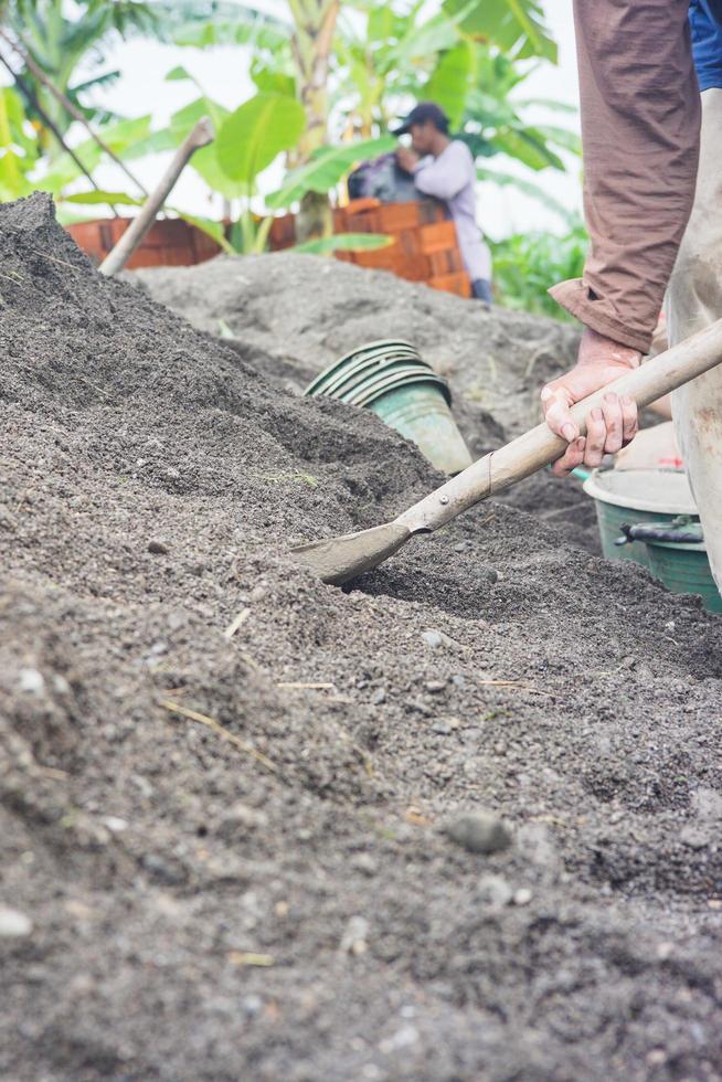 bauarbeiter, der schaufel hält, um sand als zementmischung zu sieben foto