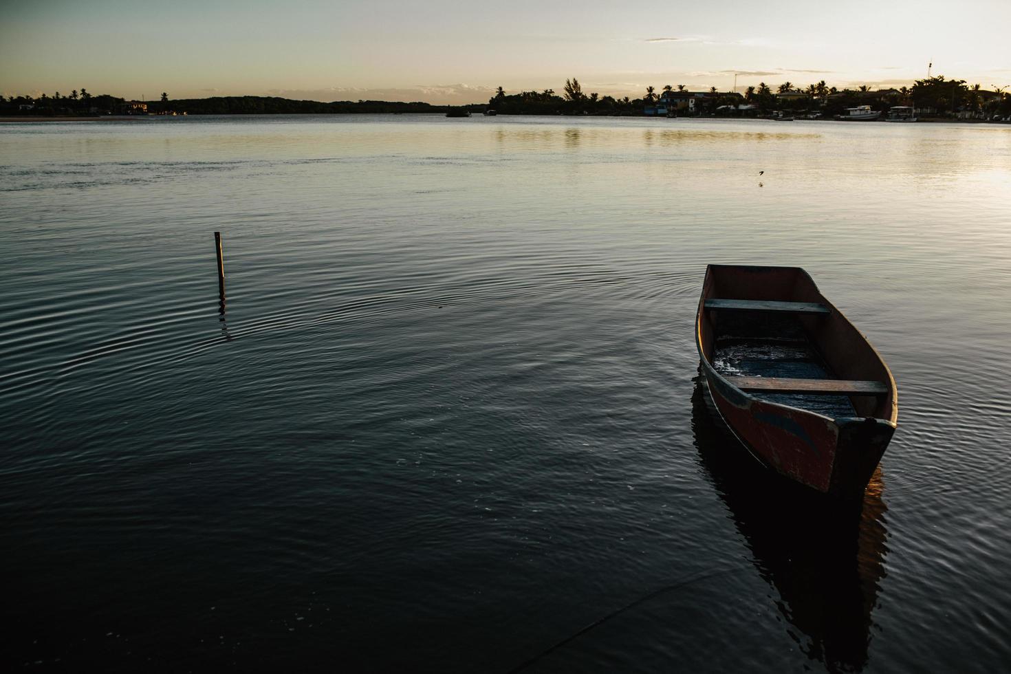 schäbiges Boot schwimmt abends auf ruhigem See foto