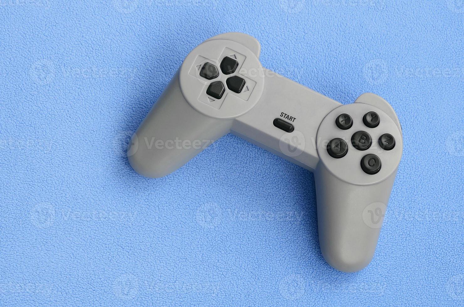 Spielkonzept spielen. Ein Pad-Joystick liegt auf der Decke aus pelzigem blauem Fleece-Stoff. Controller für Videospiele auf einer Hintergrundstruktur aus hellblauem, weichem Plüsch-Fleece-Material foto