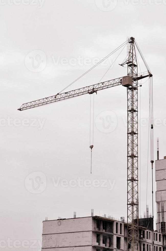 arbeitende hohe Kräne im Inneren mit hohen Gebäuden im Bau vor einem strahlend blauen Himmel. Fortschritt der Kran- und Bauarbeiten. Retro-Ton foto