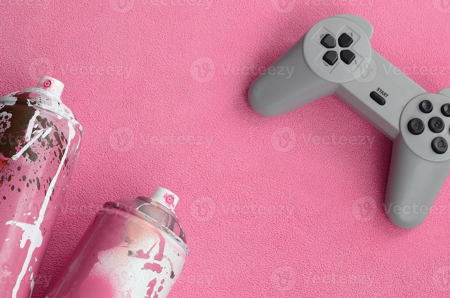 Teenager und Jugend-Lifestyle-Konzept. Joystick und zwei Spraydosen liegt auf der Decke aus flauschigem rosa Fleecestoff. Controller für Videospiele und Farbdosen auf einem Hintergrund aus Plüschvlies foto