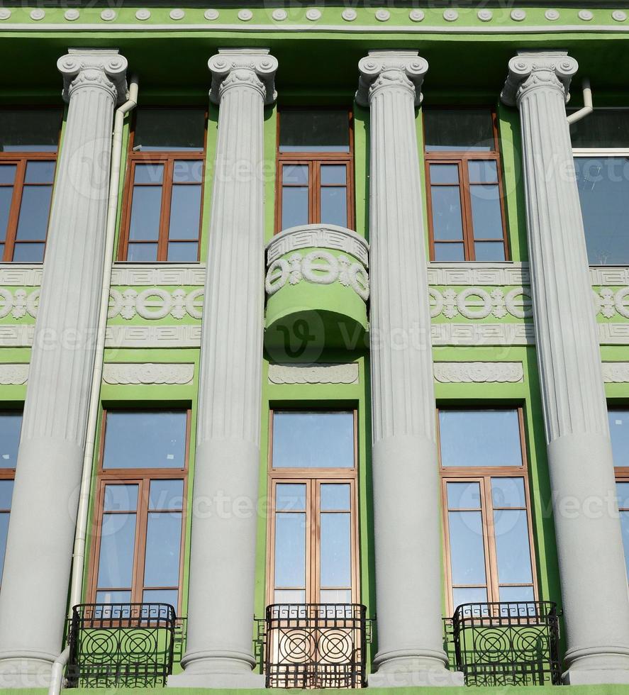 restauriertes altes mehrstöckiges Gebäude mit antiken Säulen, grün gestrichen foto