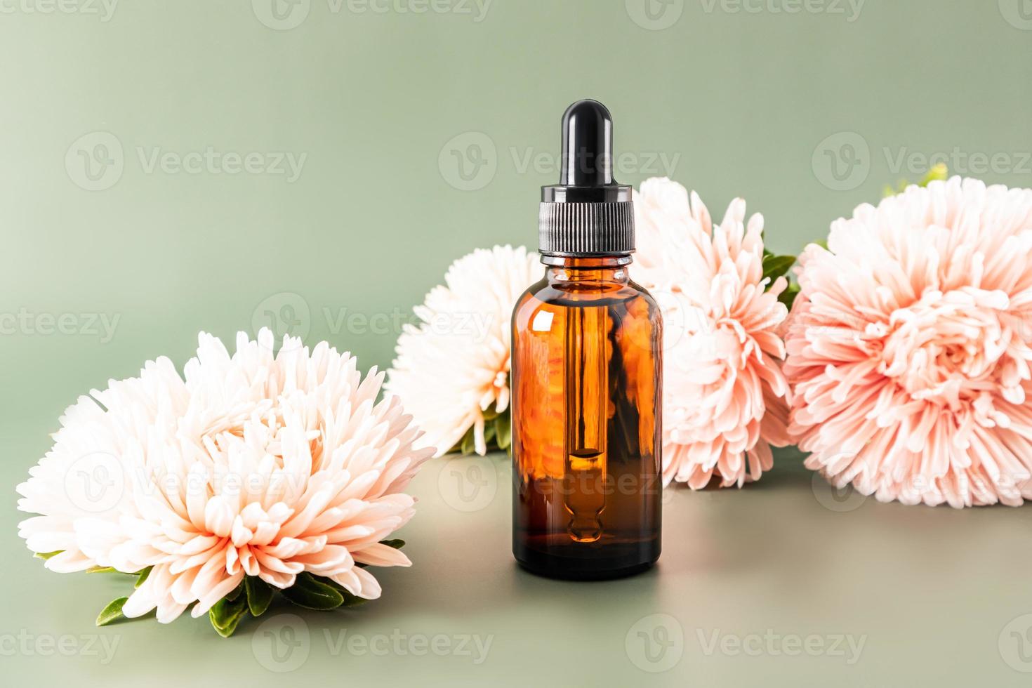 Gesichtsserum in einer Kosmetikflasche mit einer Pipette vor dem Hintergrund von Herbstblumen. einzigartige Wirkkosmetik. Vorbeugung altersbedingter Veränderungen. foto
