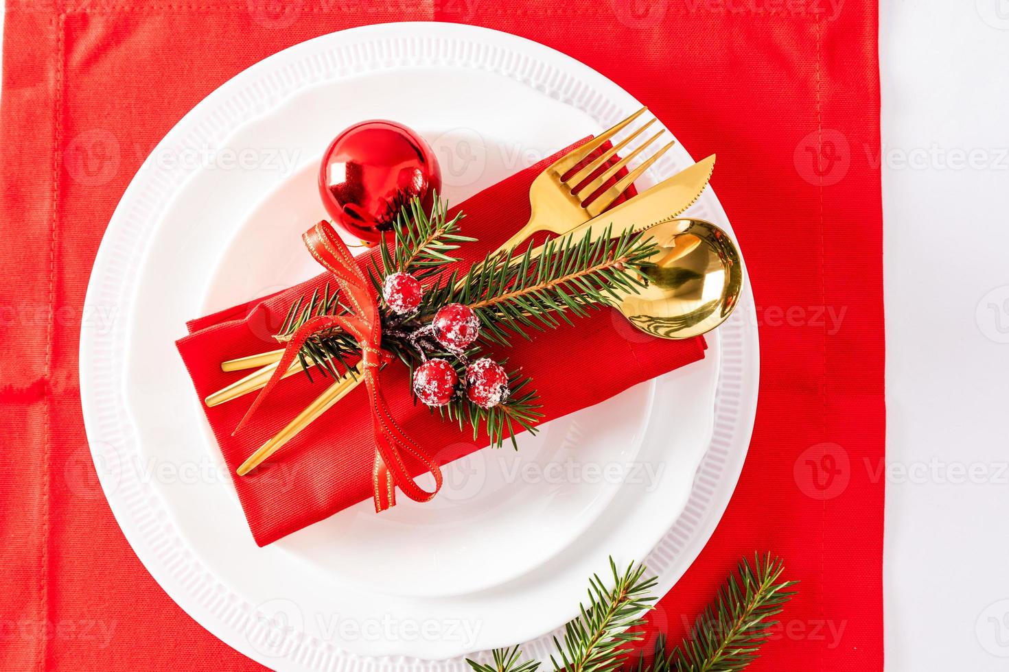 Servieren eines Weihnachtstisches mit einer Reihe von weißen Tellern, goldenen Tischplatten und weihnachtlichen Serviettendekorationen. Ansicht von oben. foto