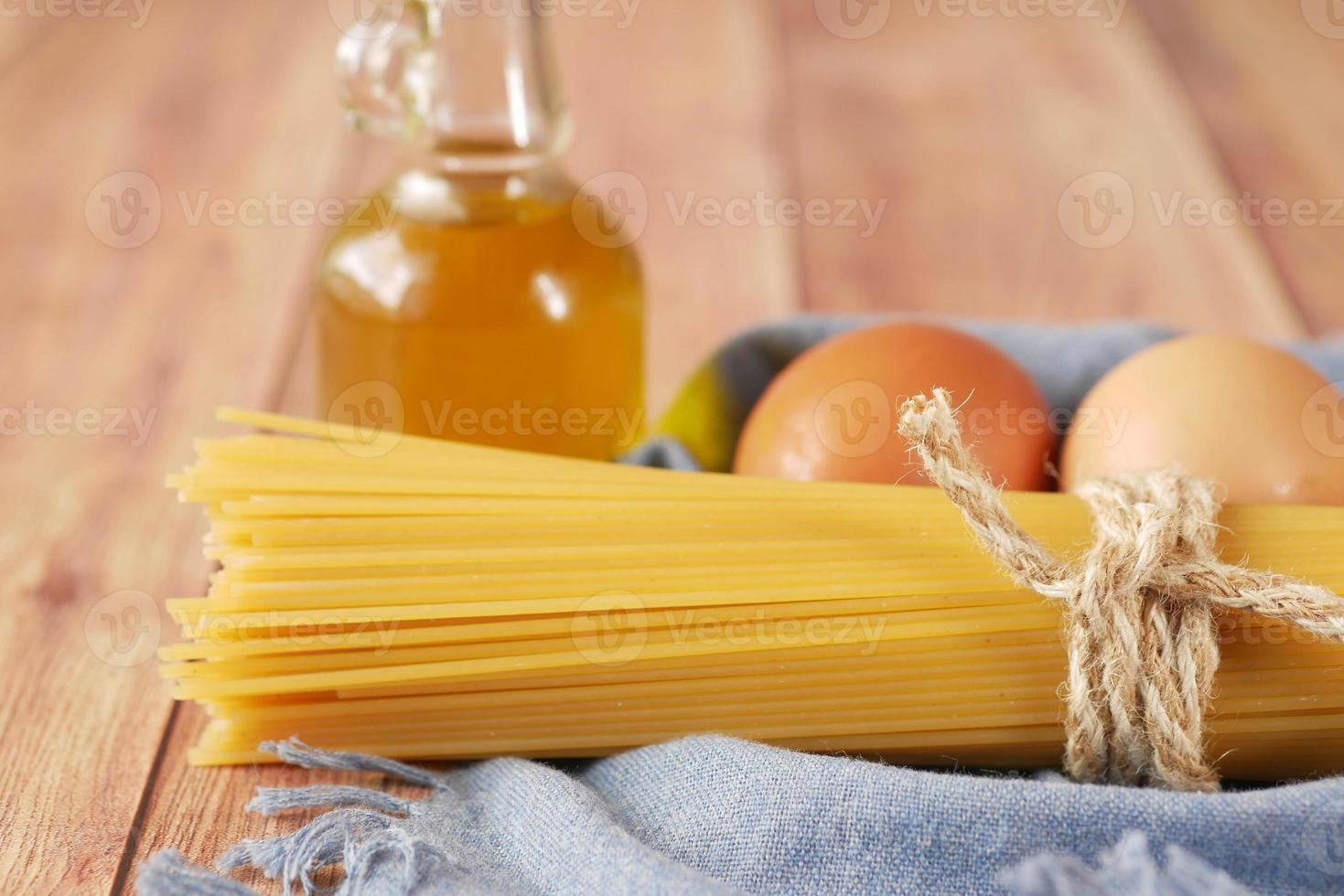 Gelbes langes Spaghetti-Ei und Öl auf dem Tisch foto