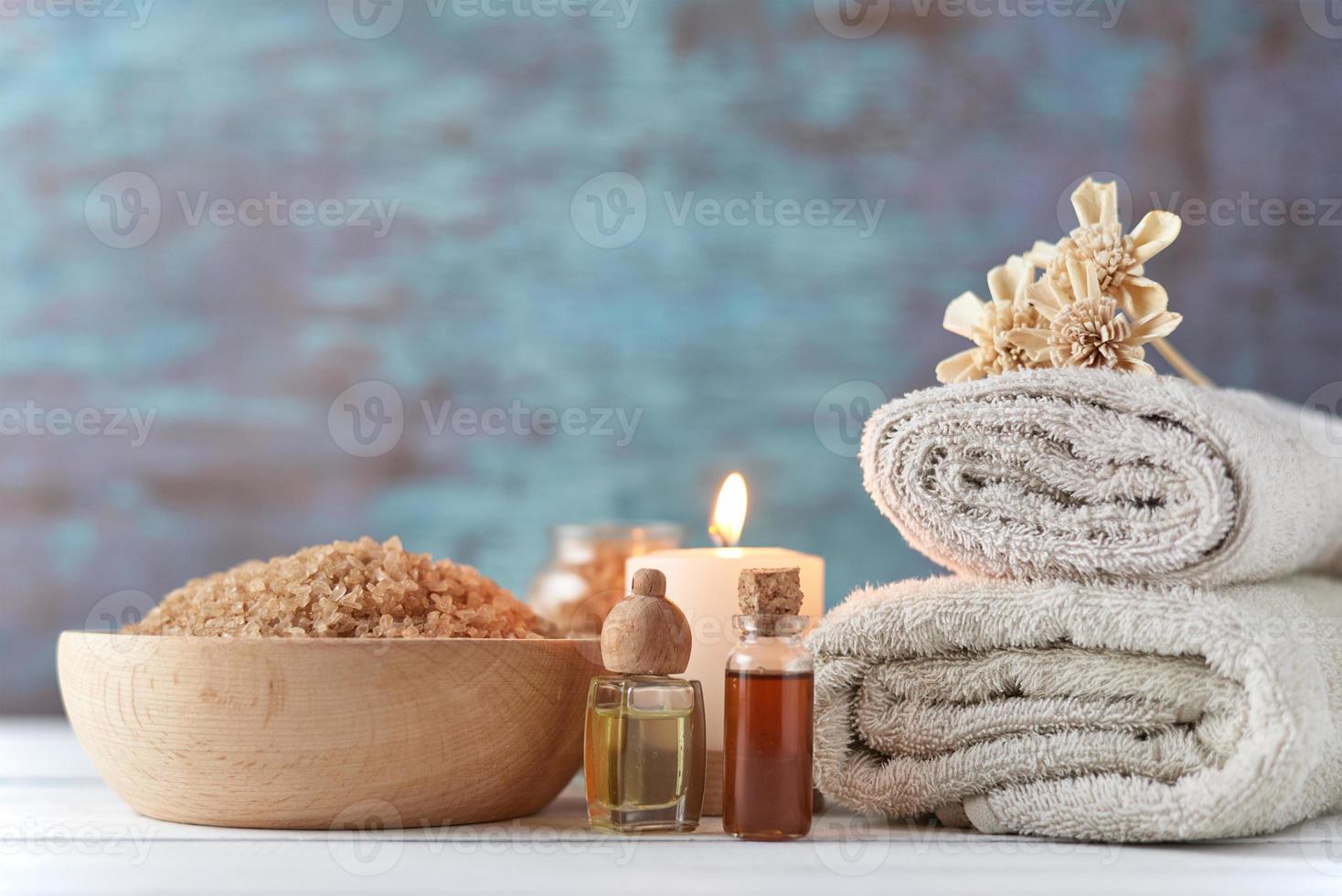 handtücher, kerze und massageöl auf weißem tisch foto