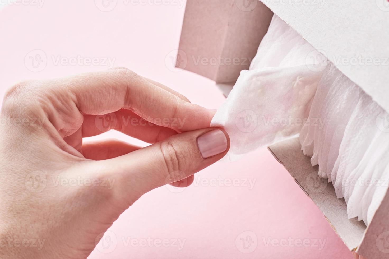 Frauenhand nimmt eine Damenbinde aus der Schachtel, Nahaufnahme foto