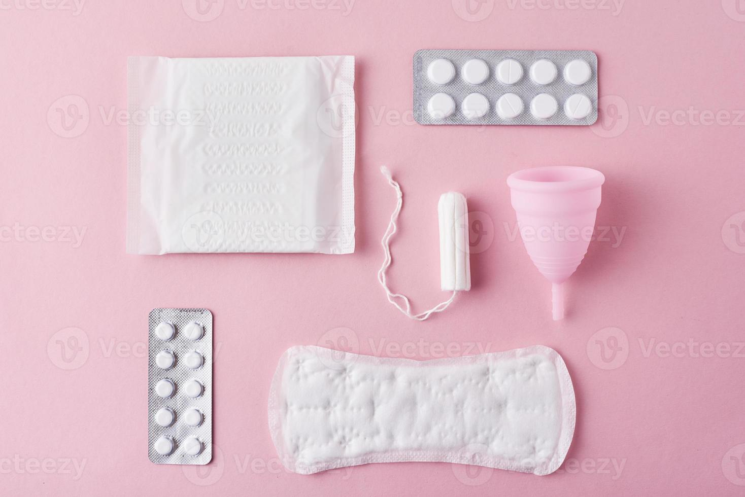 damenbinde, menstruationstasse, tampon und tabletten auf rosa hintergrund, draufsicht foto