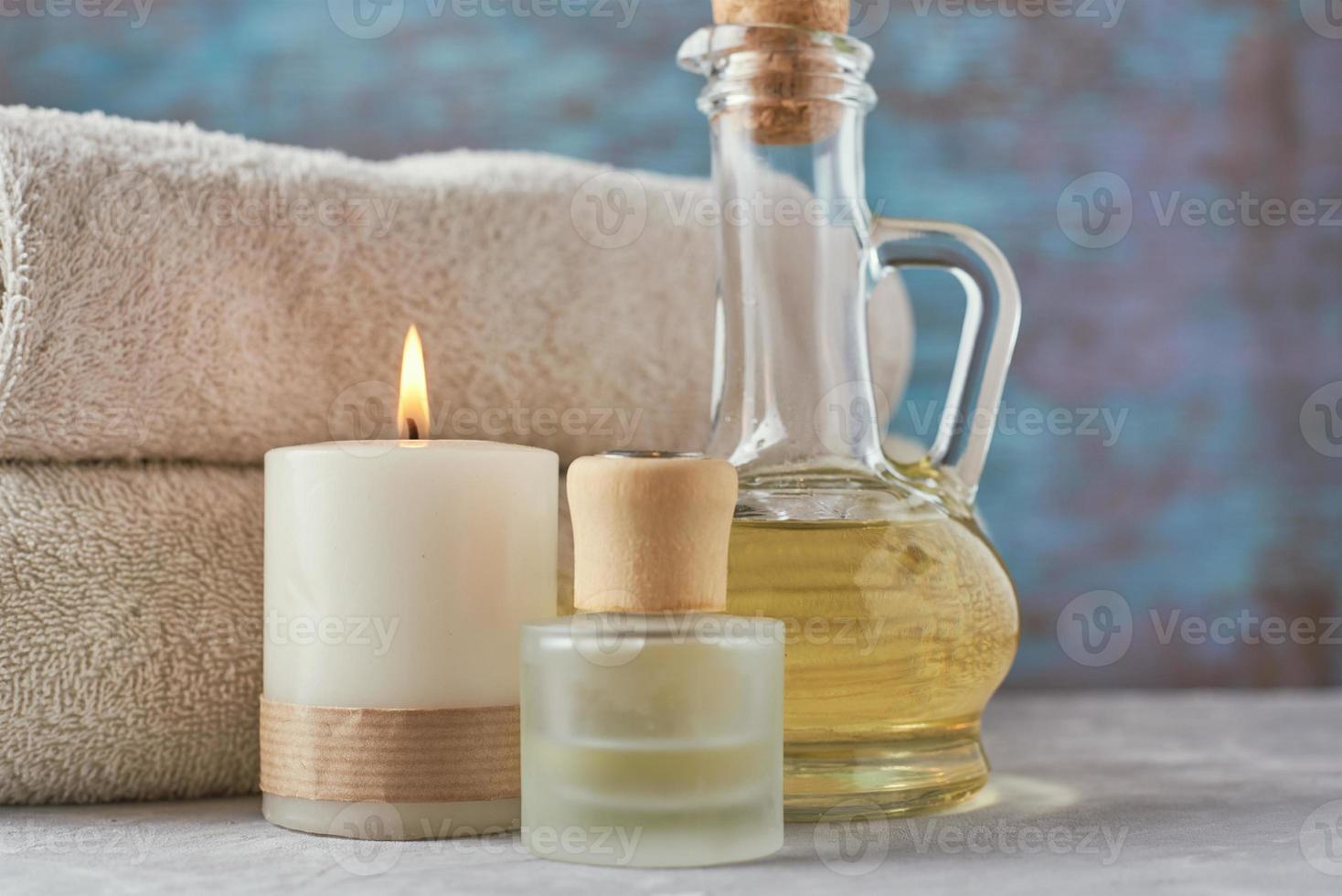 handtücher, kerze und massageöl auf weißem tisch foto