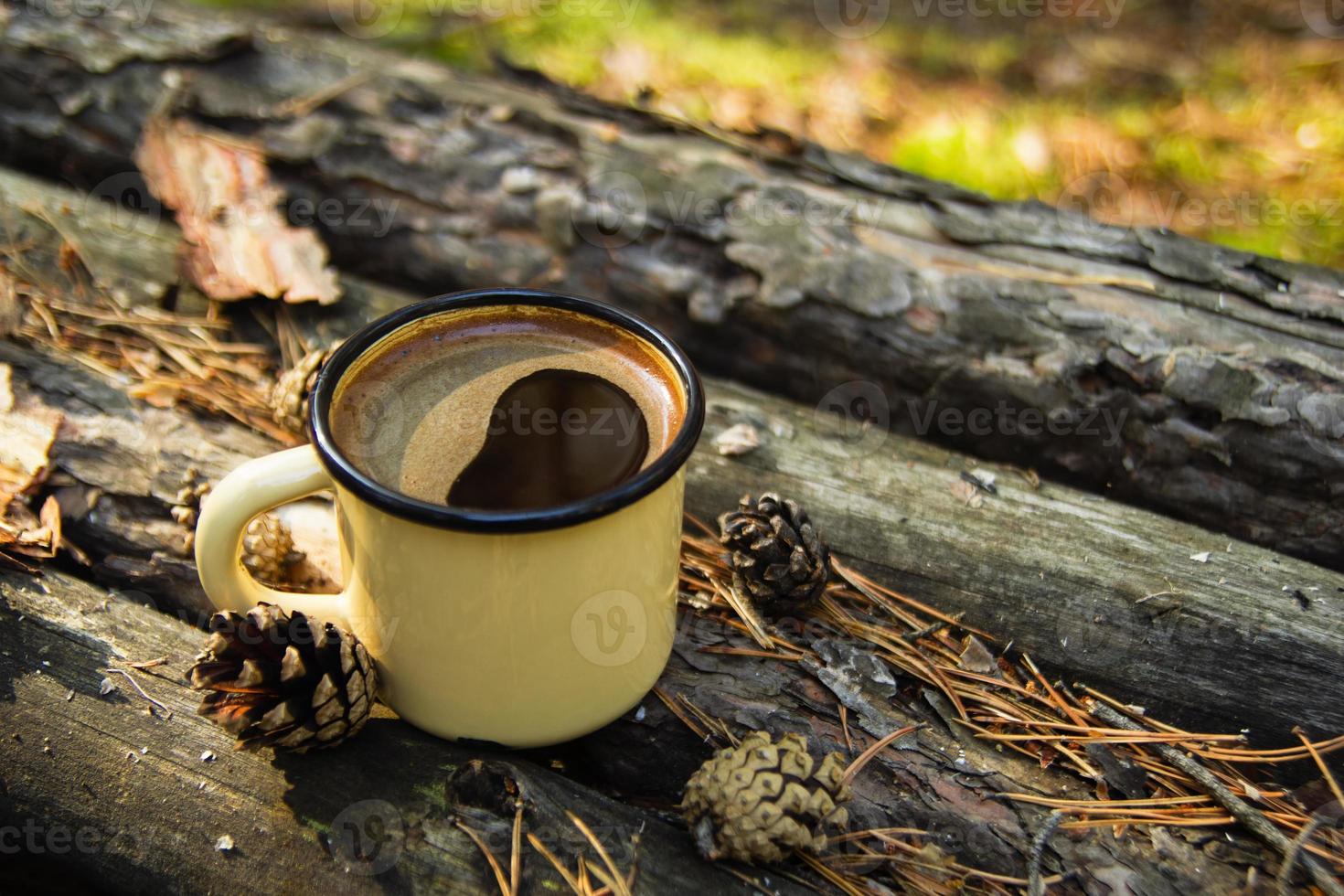 Gelbe Metalltasse mit heißem Kaffee auf dem Holzhintergrund mit Münzen, Nadeln und Baumrinde. foto