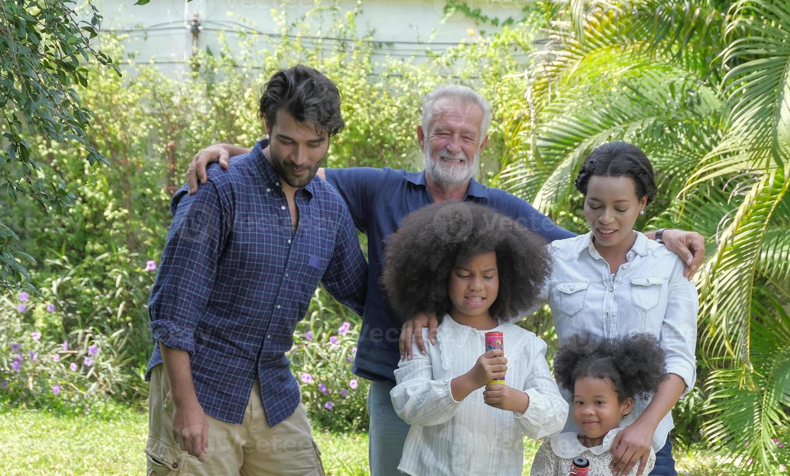 multiethnische kaukasische - afrikanische familiengruppe entspannen sich bei einem spaziergang und bereiten sich auf eine gemeinsame feier im urlaub im hinterhofhaus mit einem glücklichen lächelnden gesicht vor. selektiver Fokus. foto