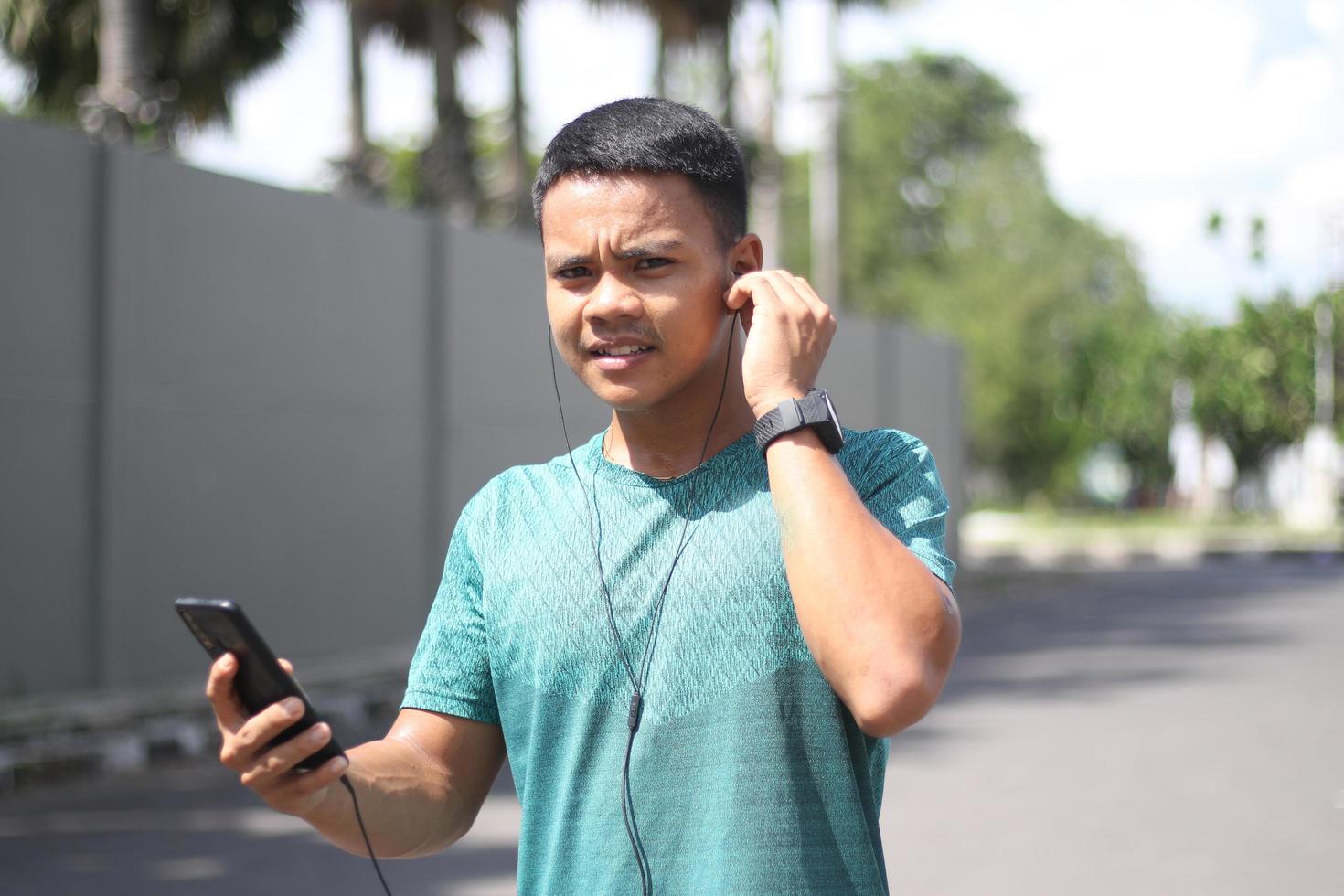 junger asiatischer junge, der sich morgens zum joggen aufwärmt und musik hört foto