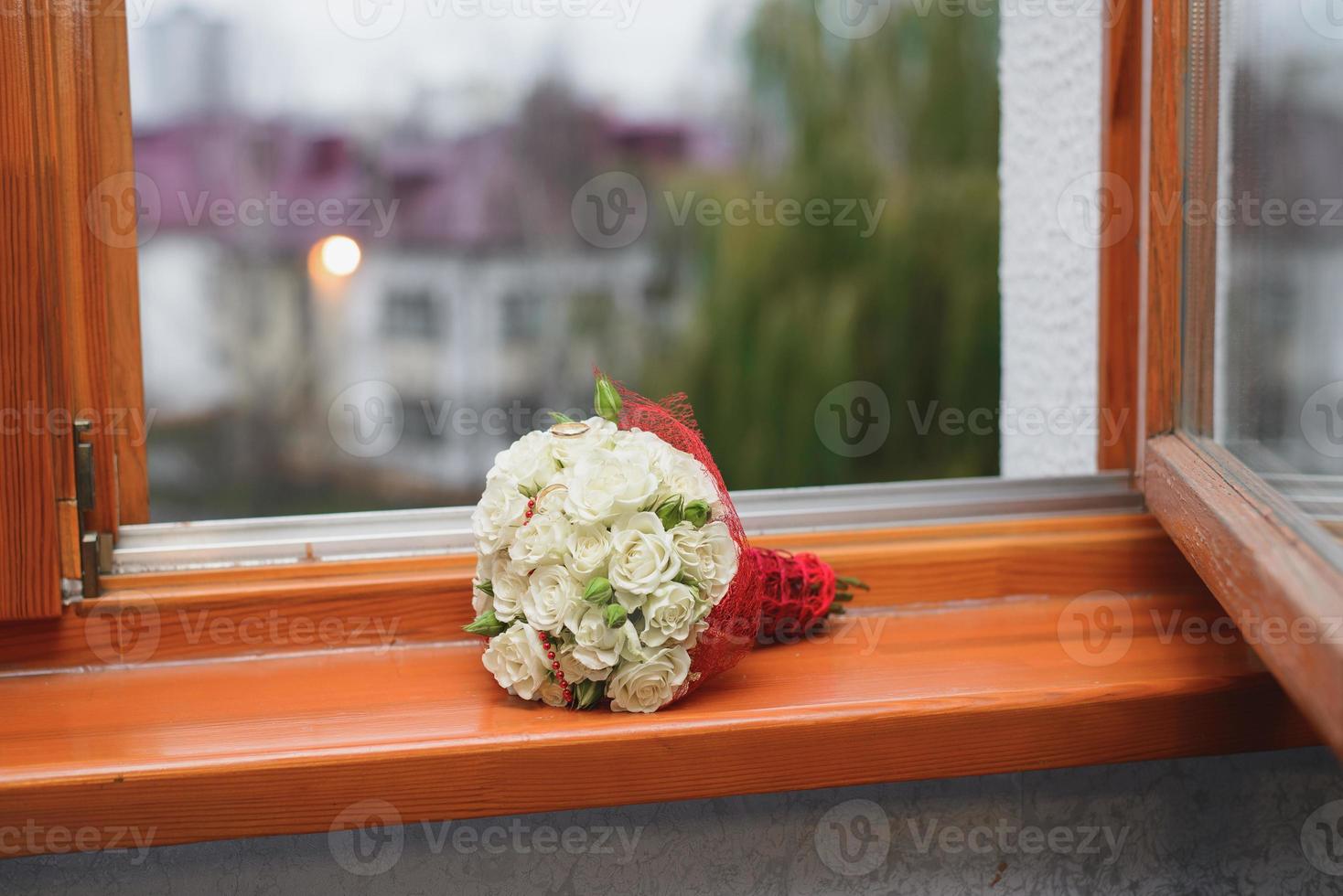 der hochzeitsstrauß der braut aus weißen rosen liegt auf der fensterbank foto