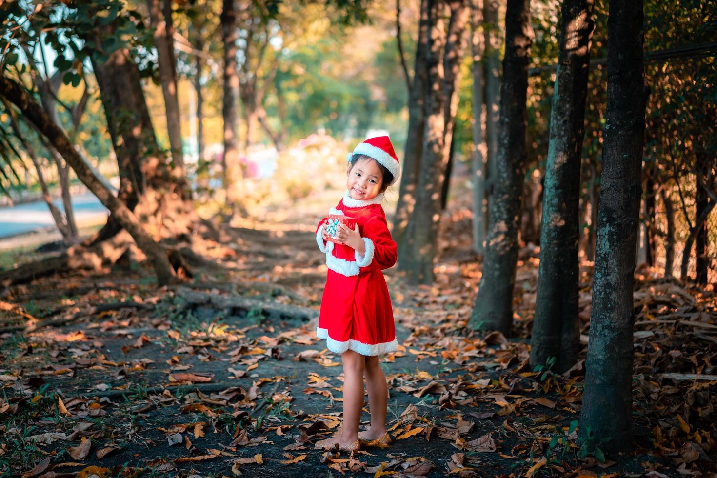 asiatisches Mädchen im roten Weihnachtsmannkostüm mit Geschenkbox foto