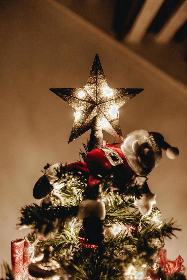 beleuchteter Stern oben auf einem Weihnachtsbaum foto