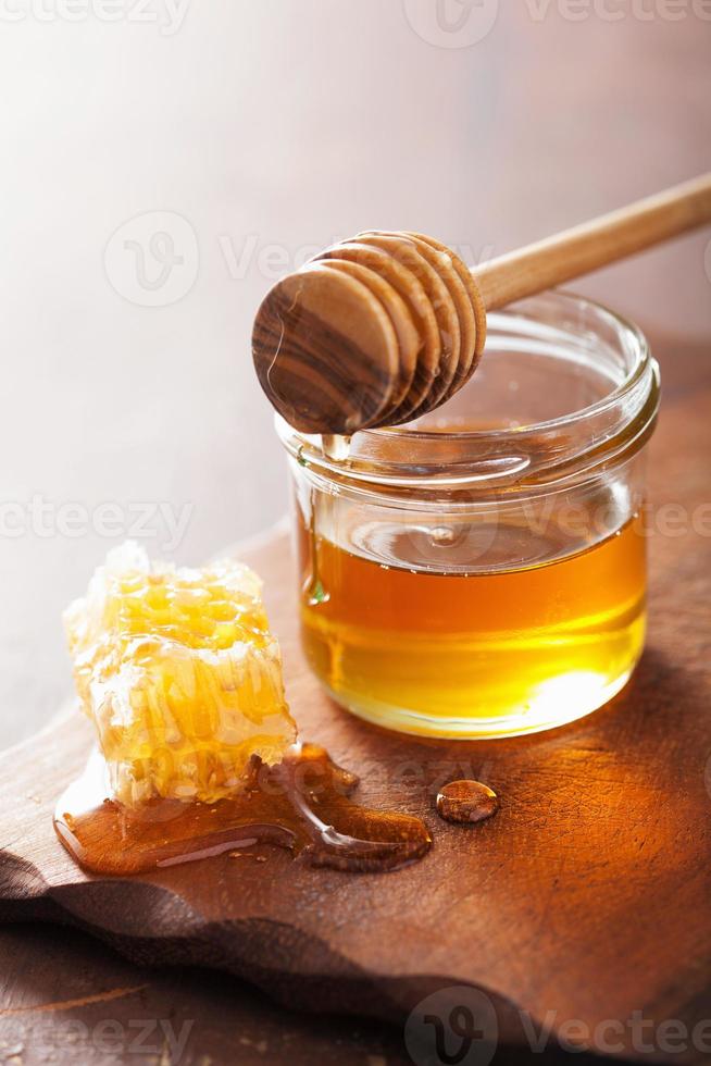 Wabenschöpflöffel und Honig im Glas auf hölzernem Hintergrund foto