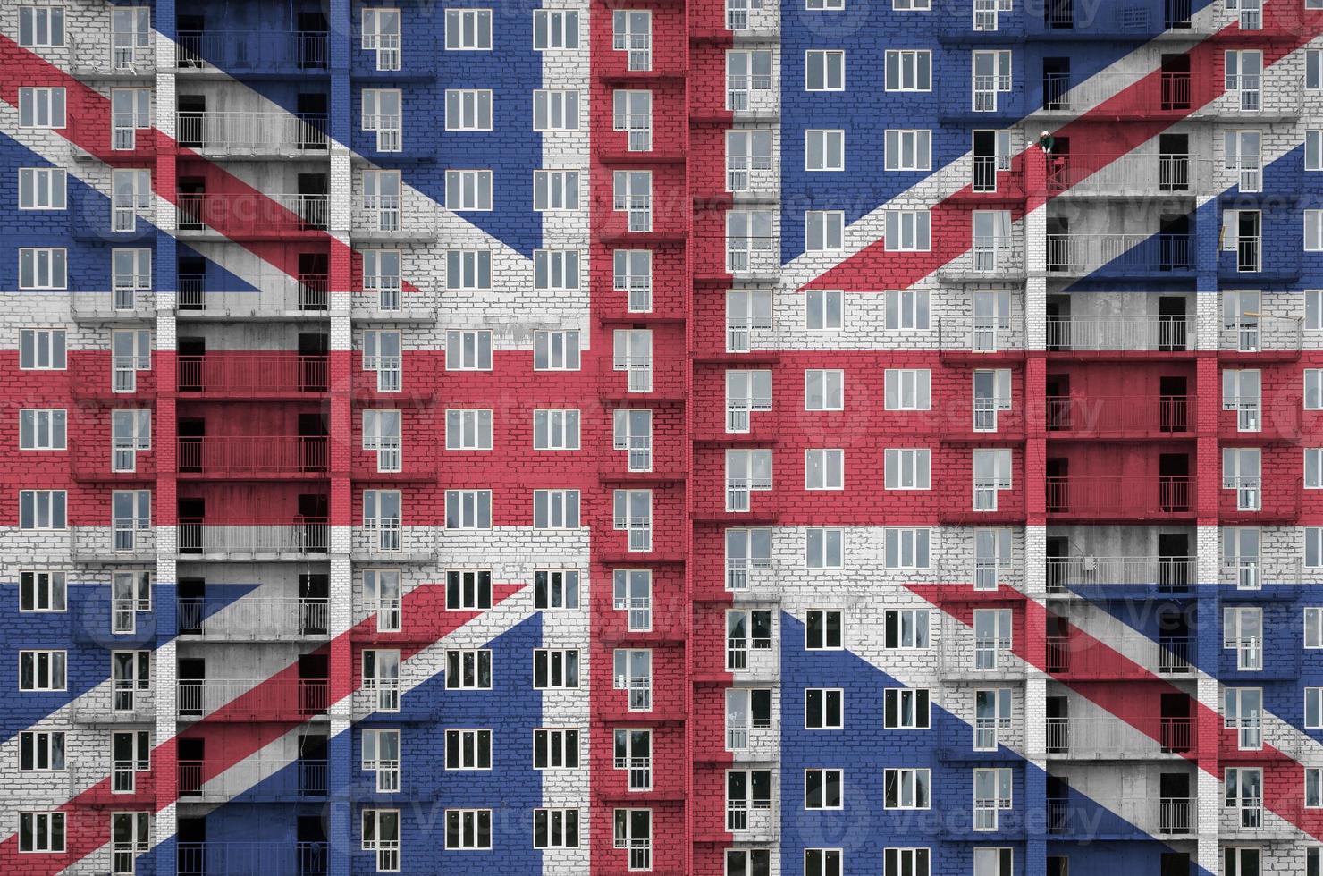 Großbritannien-Flagge in Lackfarben auf im Bau befindlichen mehrstöckigen Wohngebäuden dargestellt. strukturiertes banner auf backsteinmauerhintergrund foto