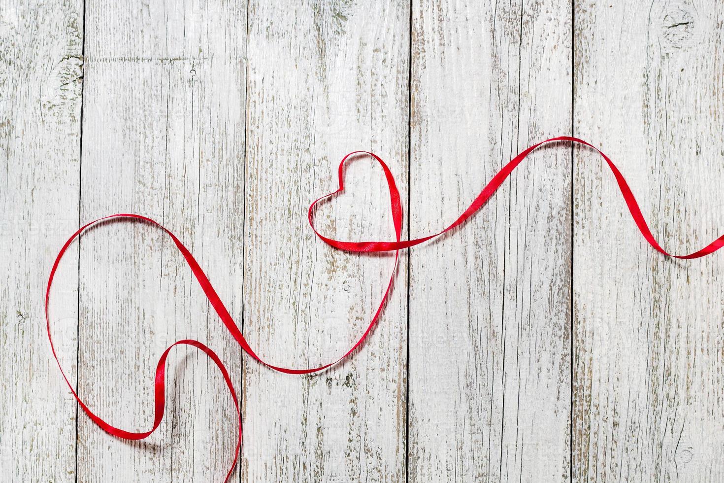 fröhlichen Valentinstag. rotes bandherz auf weißem hölzernem hintergrund foto