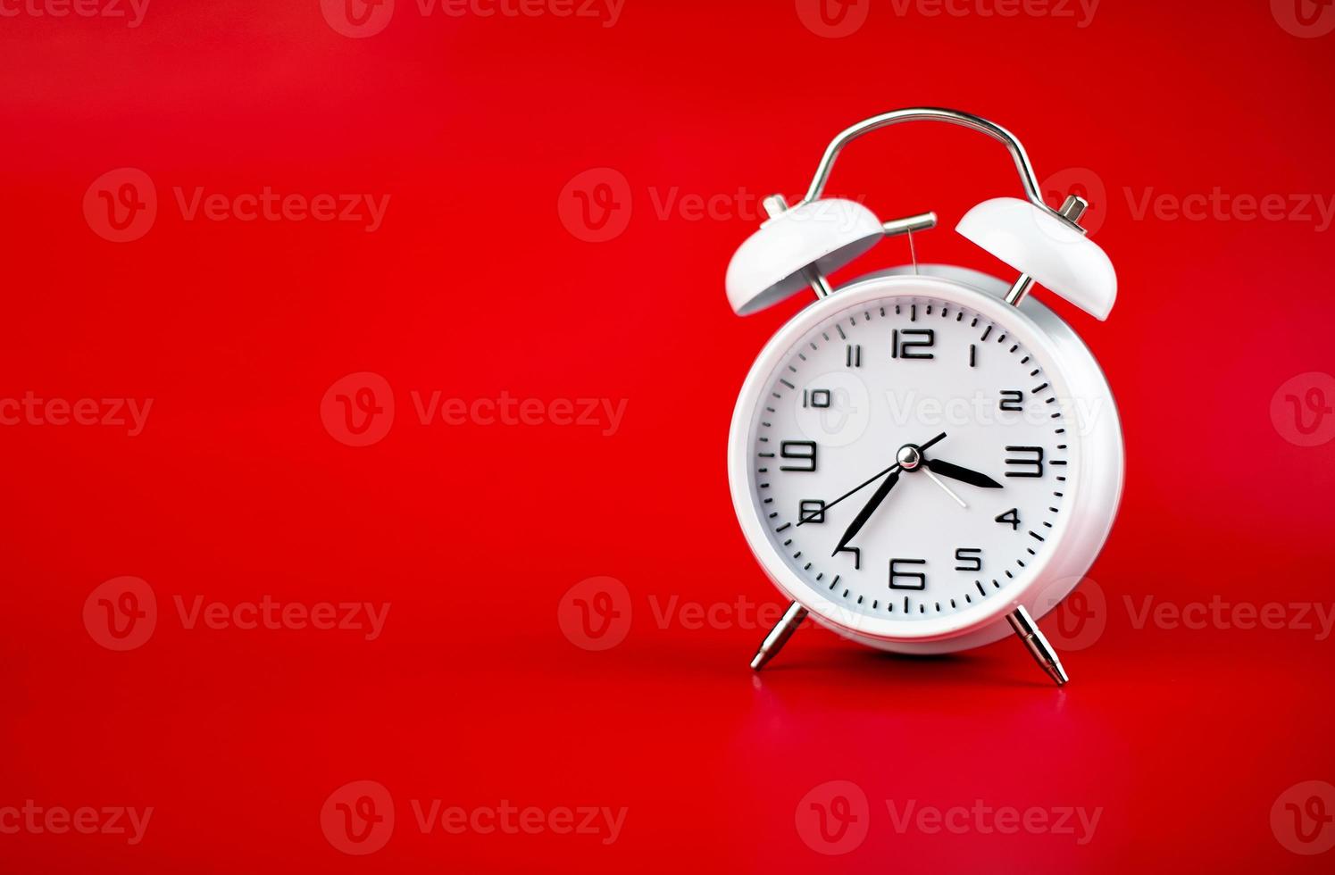 weißer Wecker auf rotem Hintergrund Zeitkonzept foto