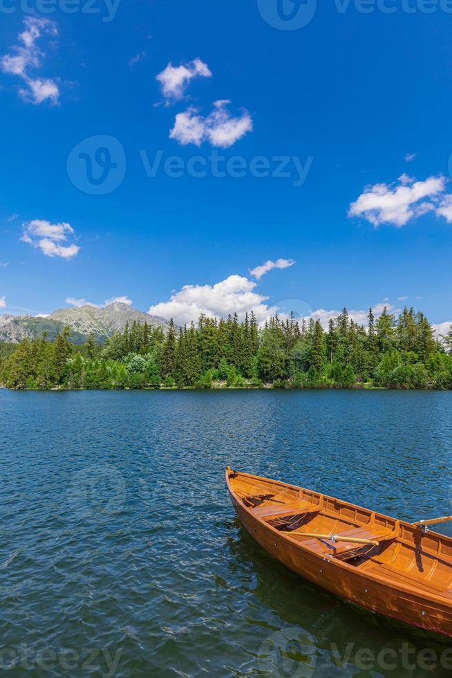 bergsee mit nadelwald, sonniger blauer himmel des holzbootes, idyllischer freiheitsreisehintergrund. romantischer Touristenort. nationalpark hohe tatra, europa. schöne naturlandschaft idyllische aussicht foto