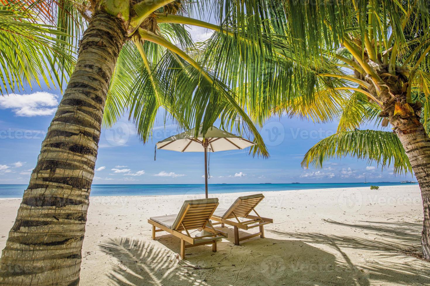 tropische Strandnatur als Sommerlandschaft mit Liegestühlen, Palmenblättern und ruhigem Meer für Strandbanner. luxusreiselandschaft, schönes ziel für urlaub oder urlaub. Strandszene foto