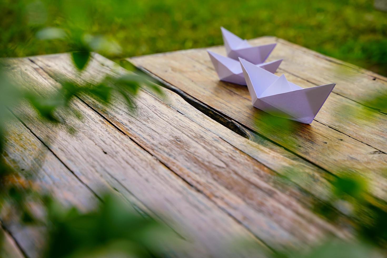 Origami, weißes Papierboot isoliert auf einem Holzboden. Papierboote bedeuten Gehen. Gefühl der Freiheitsführung foto