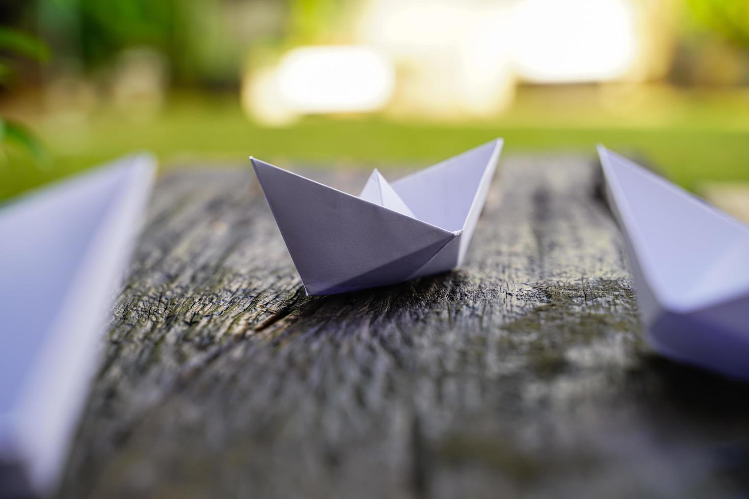 Origami, weißes Papierboot isoliert auf einem Holzboden. Papierboote bedeuten Gehen. Gefühl der Freiheitsführung foto