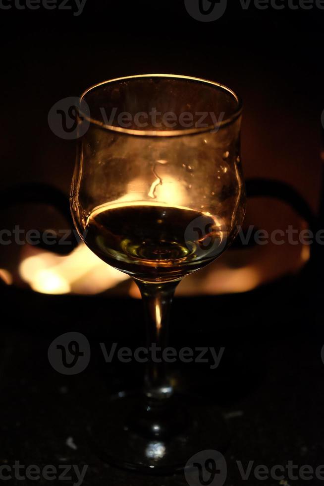 Glas Wein vor dem Hintergrund eines Lagerfeuers im Kamin foto