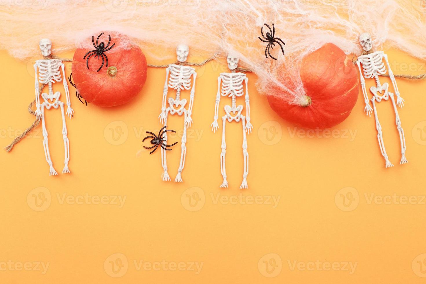 Halloween-Kürbis mit Spinnennetz, Skelett und schwarzen Spinnen auf orangefarbenem Hintergrund. foto