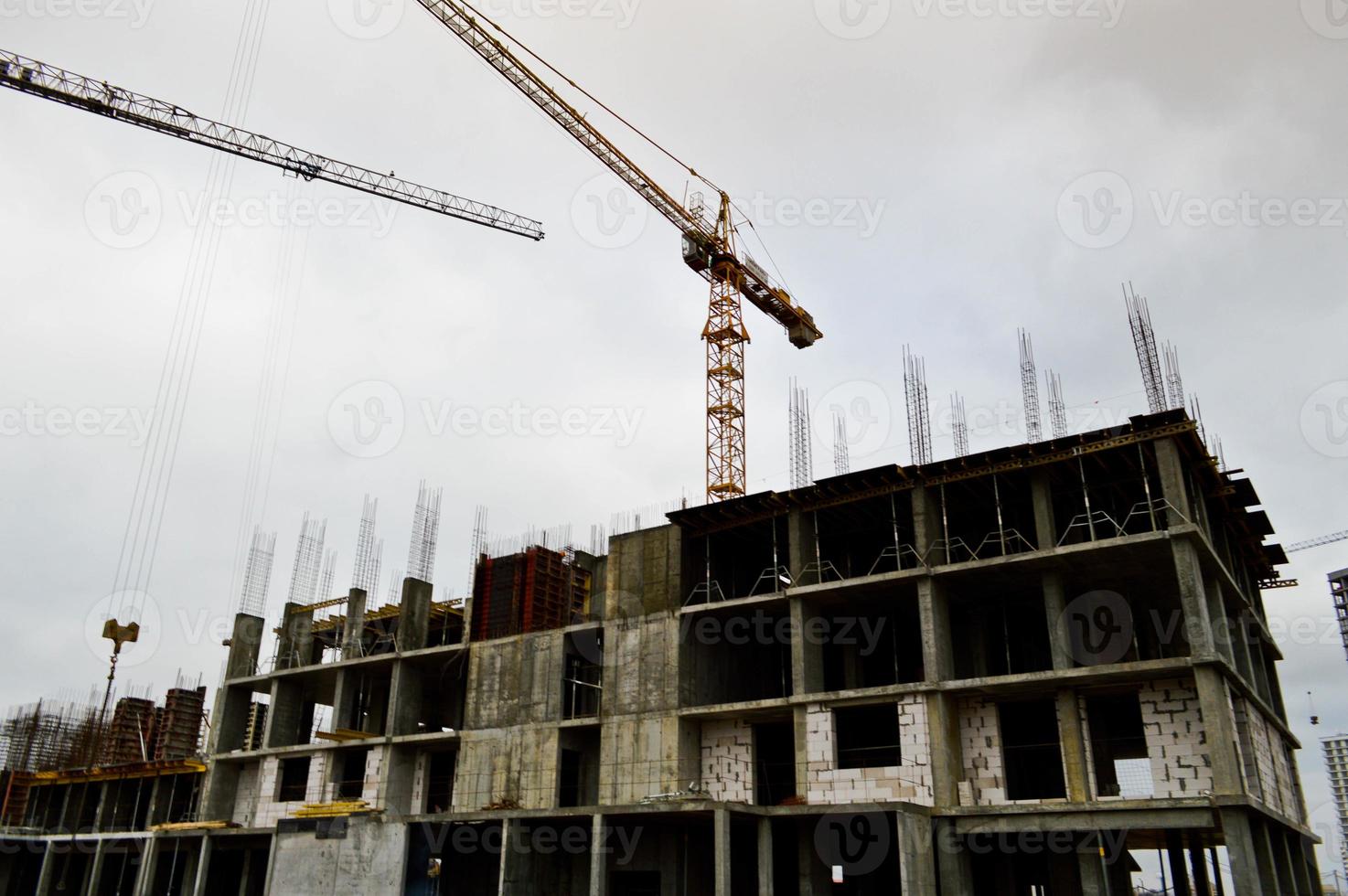 Großer leistungsstarker Industriekran für Bauladungen auf einer Baustelle mit neuen Gebäuden und Häusern gegen den Himmel foto
