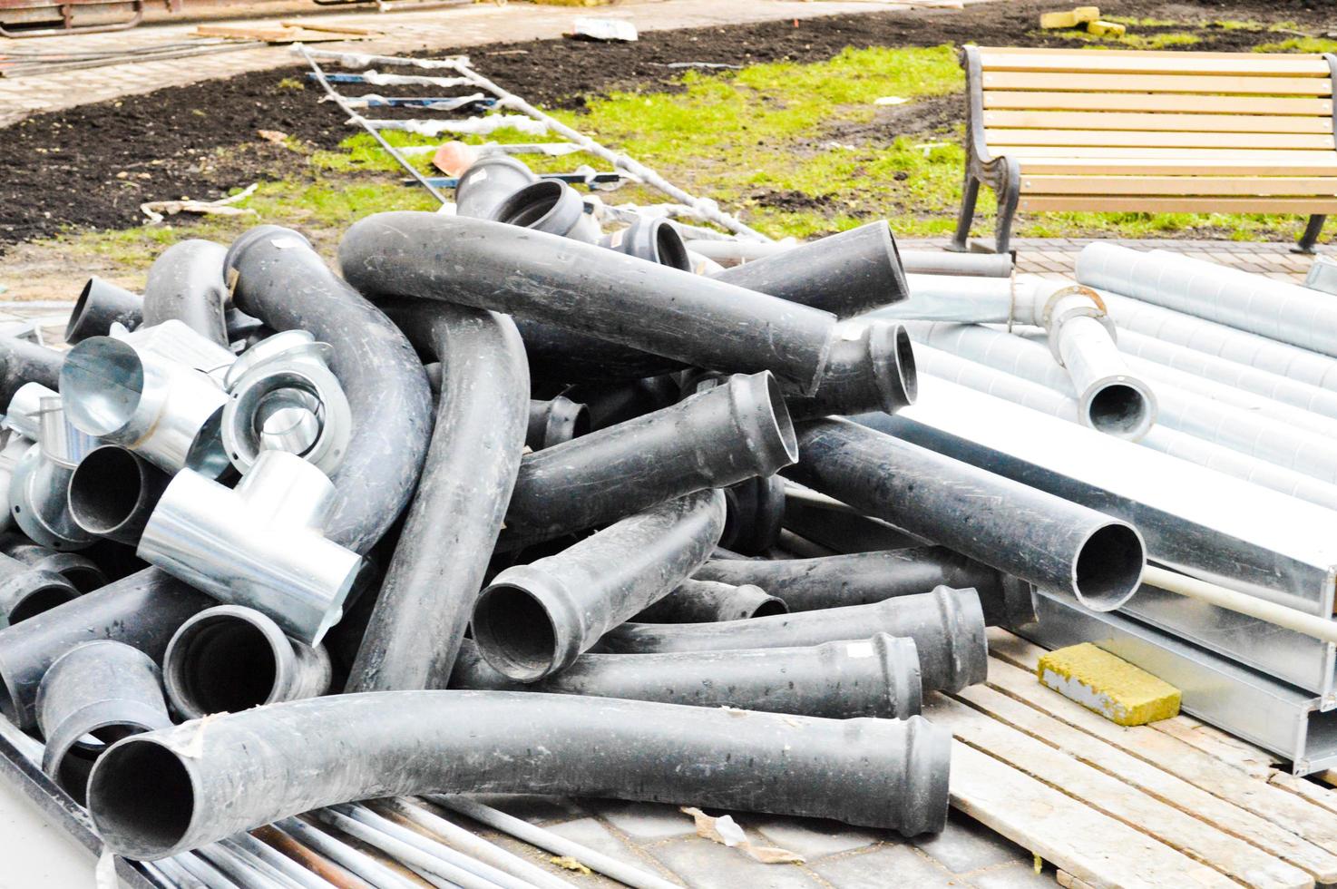 Große schwarze Kunststoff-Abwasserrohre für den Bau von Wasserleitungen oder Abwasserkanälen auf einer Baustelle während der Reparatur foto