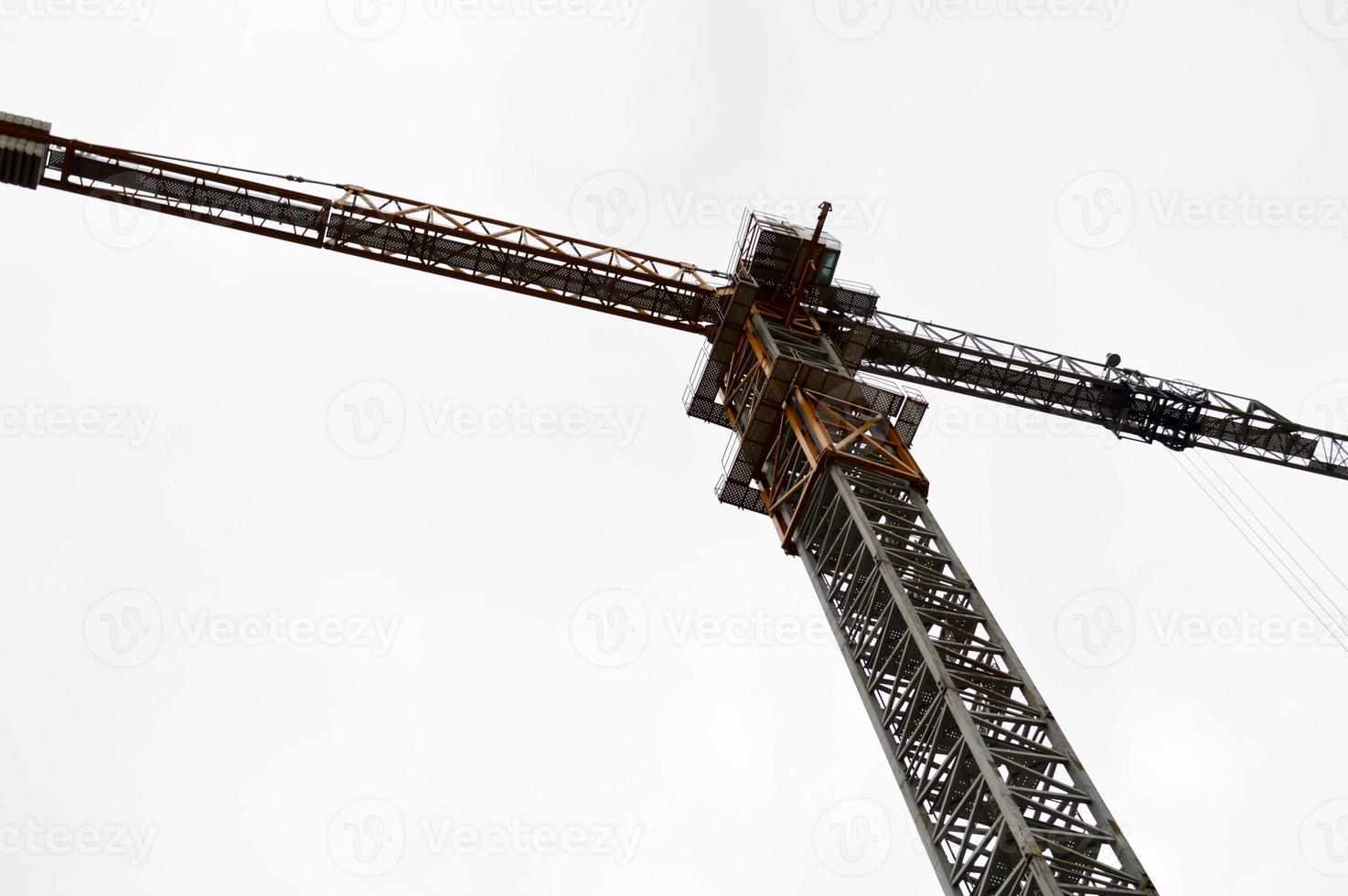 Großer leistungsstarker Industriekran für Bauladungen auf einer Baustelle mit neuen Gebäuden und Häusern gegen den Himmel foto