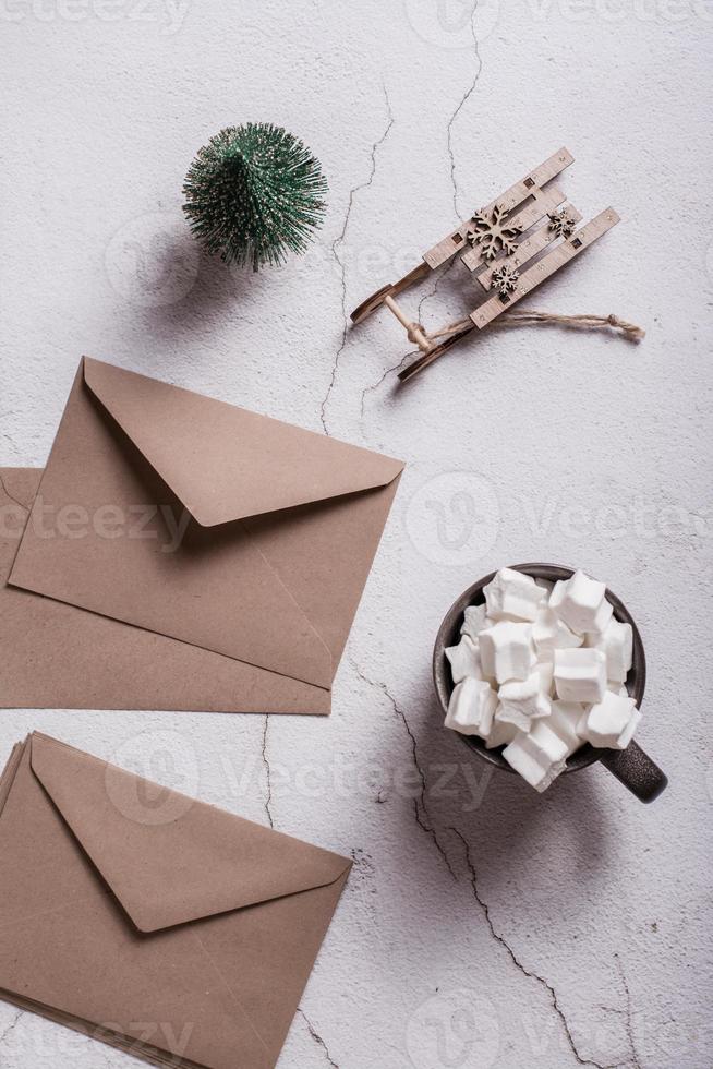 Kakao mit Marshmallows, Bastelumschläge und ein Weihnachtsbaum auf Gips. Ansicht von oben und vertikal. foto