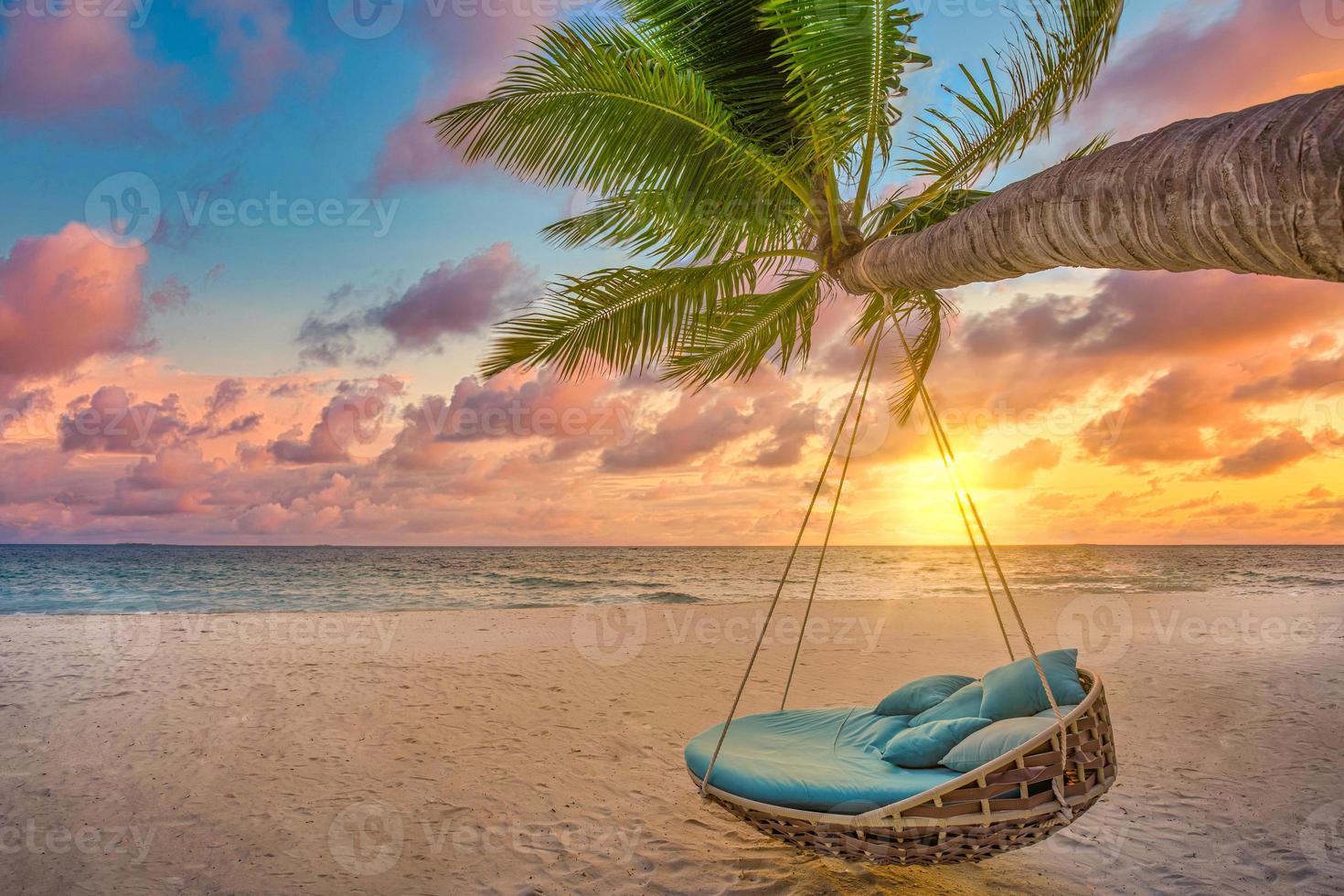 romantischer sonnenuntergang am strand. Palme mit Schaukel, die vor dem majestätischen Wolkenhimmel hängt. Traumnaturlandschaft, tropisches Inselparadies, Reiseziel für Paare. liebe küste, nahaufnahme seesand. Entspannen Sie sich am unberührten Strand foto