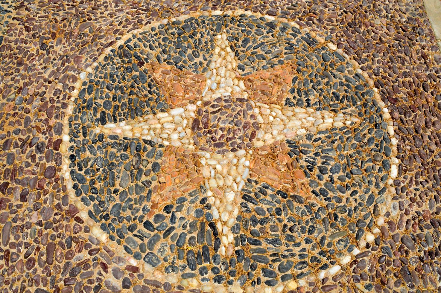 die textur der steinmauer, die straße aus kleinen runden und ovalen steinen mit abstrahierten linien von sternmustern sandnähten des natürlichen alten gelbschwarzbrauns. der Hintergrund foto