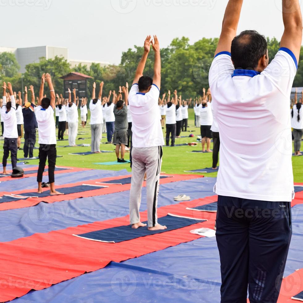 Gruppen-Yoga-Übungssitzung für Menschen verschiedener Altersgruppen im Cricket-Stadion in Delhi am internationalen Yoga-Tag, große Gruppe von Erwachsenen, die an Yoga-Sitzungen teilnehmen foto