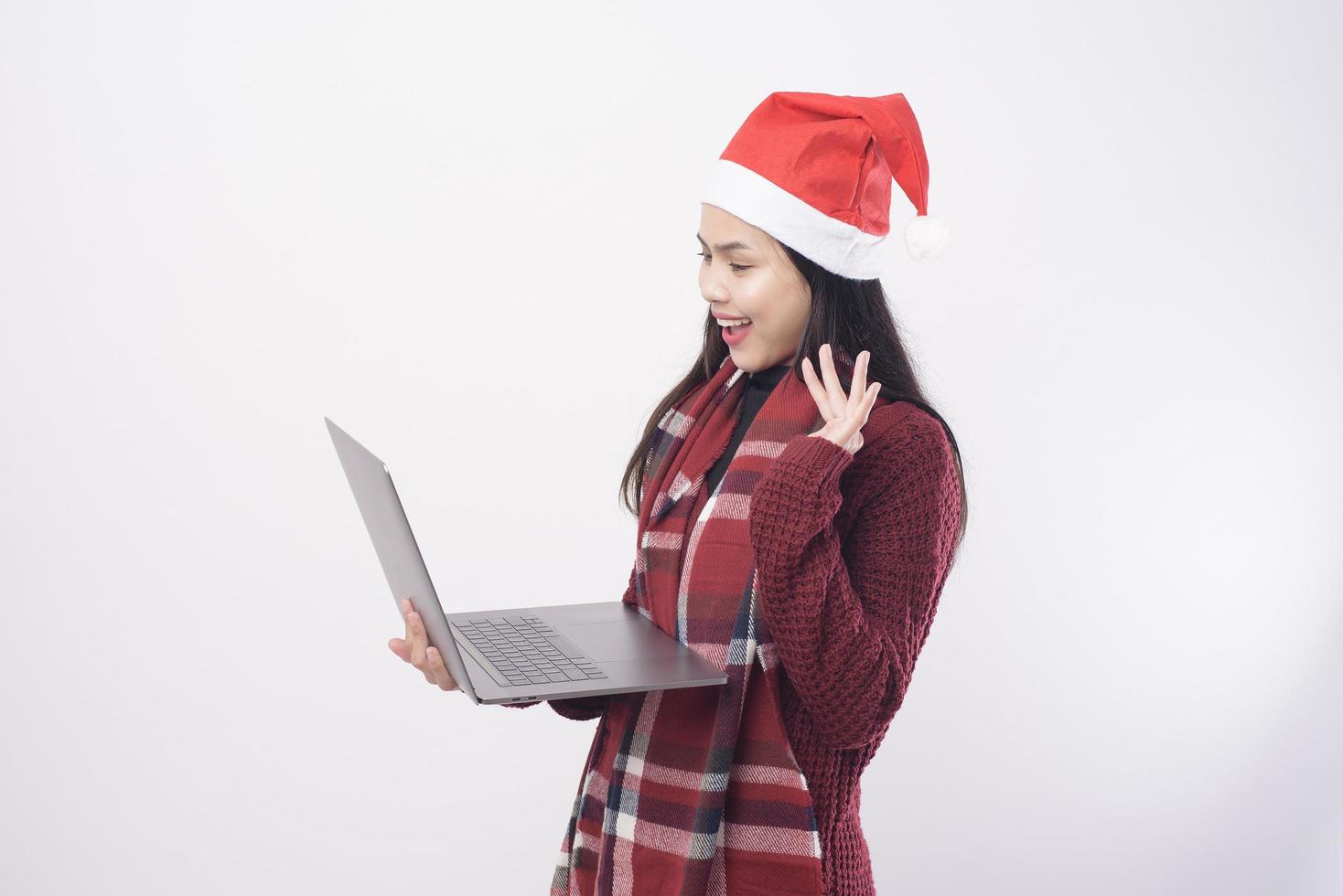 junge lächelnde Frau, die roten Weihnachtsmannhut trägt, der Videoanruf macht foto