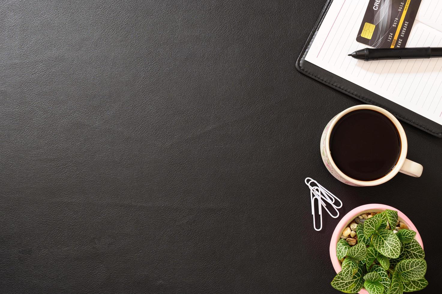 Notizbuch, Kreditkarte und eine Kaffeetasse auf dem Schreibtisch foto