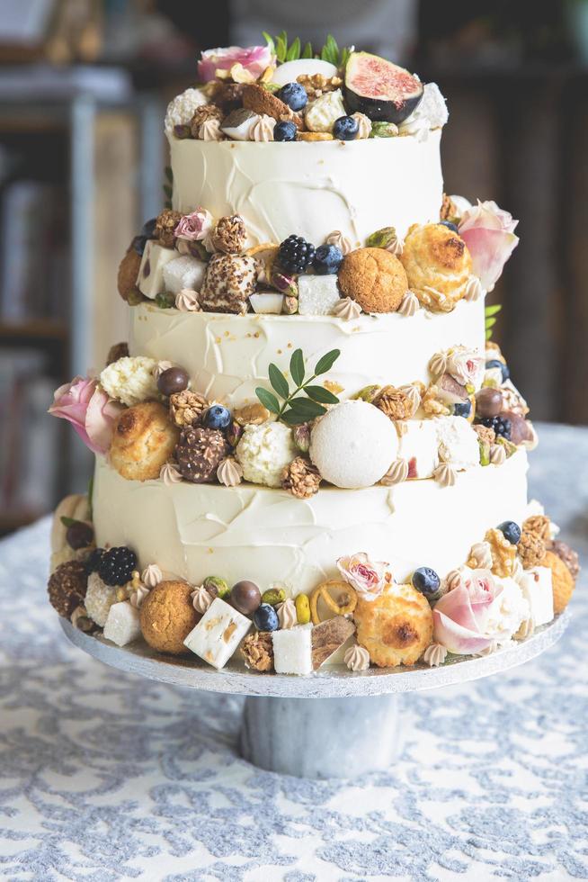 dekorative Hochzeitstorte mit Obst, Keksen, Makronen und Blumen foto