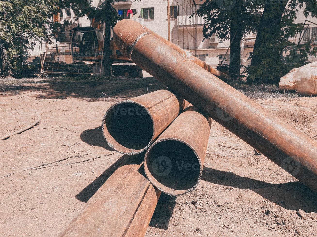 Metallrohr liegt auf dem Boden. Verlegung der Kommunikation für Wohngebäude unter der Erde. Wasser und Abwasser für Wohnungen foto