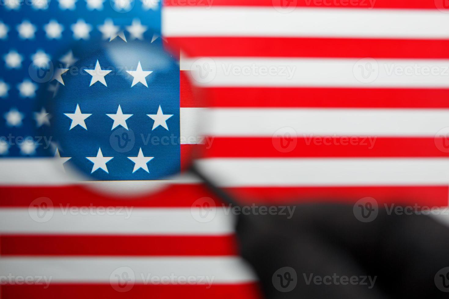 die us-flagge schaut durch ein lupenglas. totale überwachung der vereinigten staaten. das Konzept der versteckten Bedrohungen und der Kontrolle über das Land foto