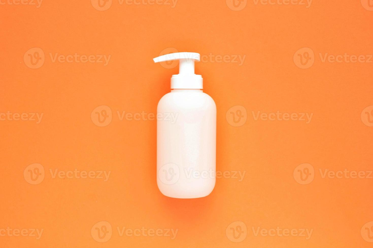 weiße, markenlose Plastikspender-Pumpflasche auf orangefarbenem Hintergrund mit Kopierraum für Text. kosmetikverpackungsmodell, flüssiger seifenflakon, händedesinfektionsmittel ohne etikett, shampoo bio spa, duschgel foto
