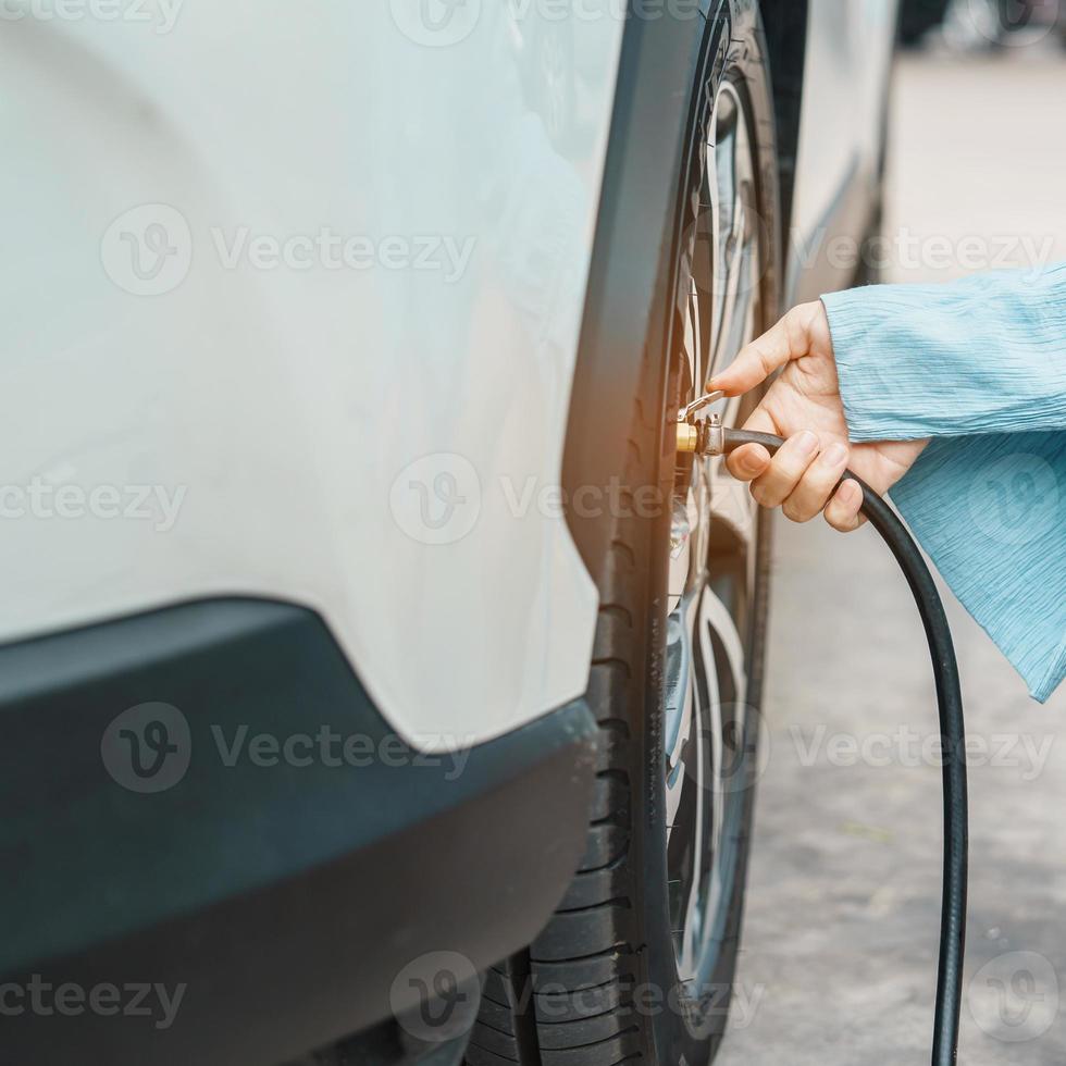 Frau Fahrer Hand Reifen des Fahrzeugs aufpumpen, Reifenventil Stickstoffkappe zum Überprüfen des Luftdrucks entfernen und Luft auf Autorad an Tankstelle füllen. Selbstbedienung, Wartung und Sicherheit foto